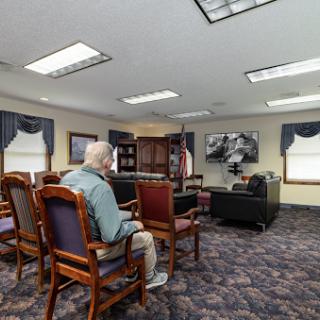 A peaceful waiting room setting, featuring an elderly person seated comfortably with a view of a television.