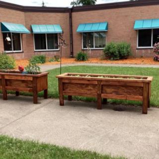 Raised planter boxes in a courtyard garden area with a building in the background.