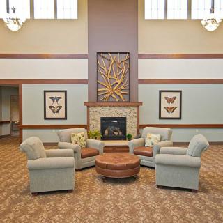 A cozy living room with a circular arrangement of armchairs and a central fireplace, decorated with framed artwork.