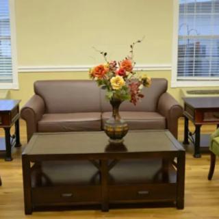 A cozy living room setup featuring a sofa and coffee table adorned with a vibrant flower arrangement.