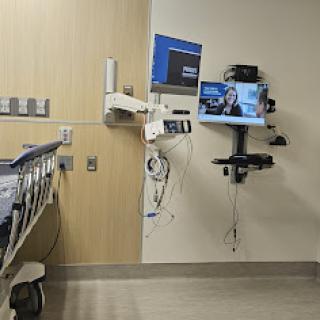 A view of a patient room in a hospital, featuring medical equipment and a hospital bed.