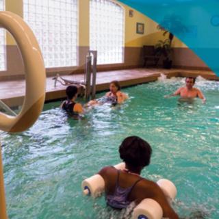 A group of people participating in a water aerobics class in an indoor pool.