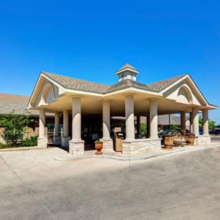 A building entrance with columns and a gabled roof under a clear blue sky.
