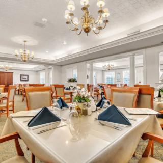 An elegant dining room with neatly set tables and chandeliers.