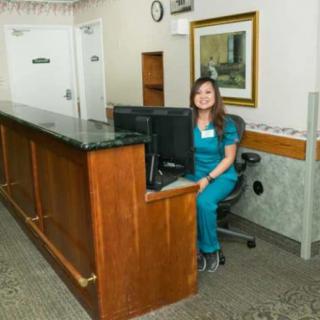 A receptionist sitting at a desk in an office, smiling at the camera.