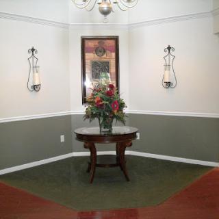 A well-decorated lobby area featuring a floral arrangement on a round table, complemented by wall sconces and a mirror.