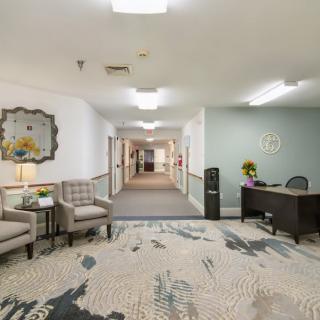 A hallway with a reception desk and seating area, featuring modern interior design elements.