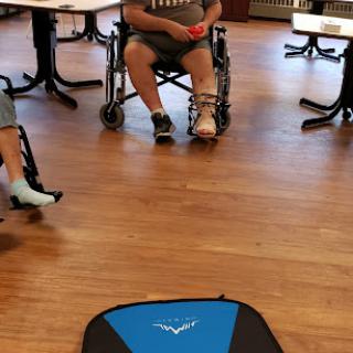 Participants engage in an activity while seated in wheelchairs within a community space.