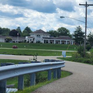 A view of a building from a winding road under a cloudy sky.