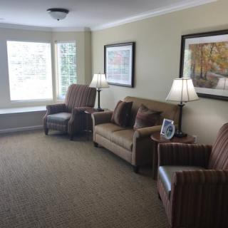 A cozy living room with a sofa, armchairs, and decorative artwork on the walls.