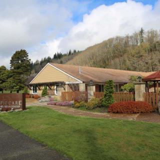 A peaceful residential house surrounded by a well-maintained garden and trees under a partly cloudy sky.