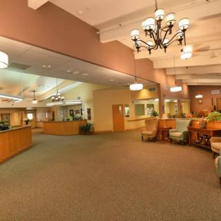 A spacious lobby area with comfortable seating and a reception desk, illuminated by chandeliers.