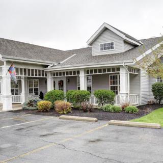 A residential-style building with a manicured lawn and small parking area in front.