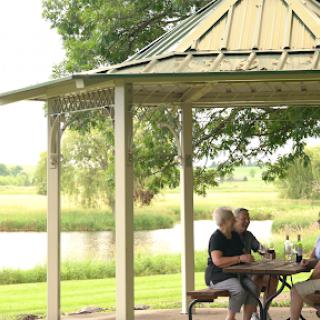 A group of friends enjoying a peaceful moment together under a gazebo by the water.