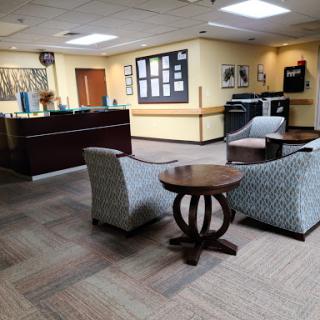 A cozy waiting area featuring stylish chairs and a wooden table, designed for comfort and relaxation.
