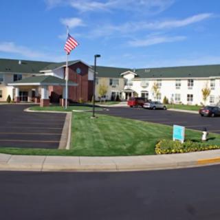 A large building with a parking lot and an American flag in front under a clear blue sky.