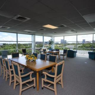 A spacious conference room with large windows offering a scenic view, equipped with a long table and several chairs.