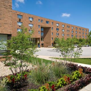 A modern brick building surrounded by lush greenery and colorful landscaping.