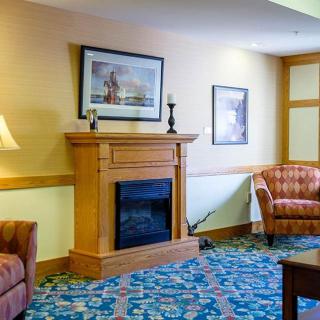 A cozy living room featuring a fireplace, armchairs, and decorative elements.