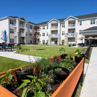A modern residential complex with a landscaped garden area and outdoor seating.