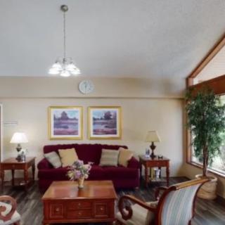 A cozy living room featuring a plush sofa, wooden coffee table, decorative lamps, and framed artwork on the wall.