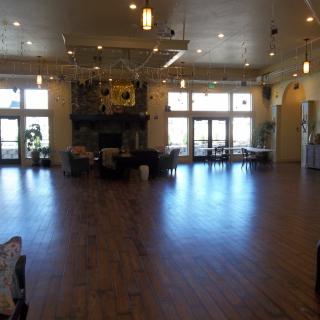 Spacious hall with wooden flooring and large windows.