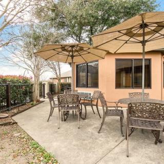 A cozy backyard patio with tables, chairs, and large umbrellas.
