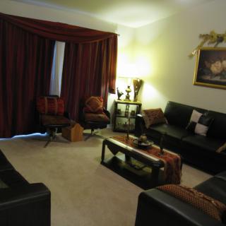 A cozy living room with dark furniture and warm lighting.