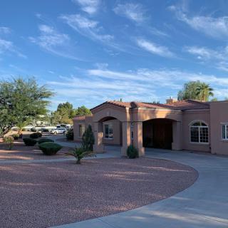 A beautiful residential building set against a clear blue sky, surrounded by desert landscaping.