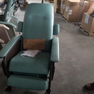 A teal medical chair, designed for comfort and support, set against a backdrop of boxes.