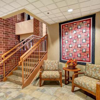 A cozy waiting area with comfortable seating and a vibrant quilt wall hanging.
