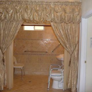 An accessible bathroom with elegant curtains and tiled walls.
