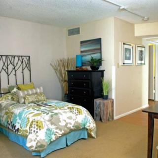 A cozy bedroom with a decorative headboard, colorful bedding, and modern furnishings.
