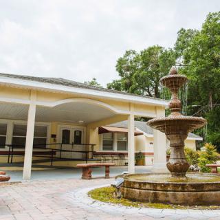 A serene building exterior with a prominent fountain and surrounding greenery.