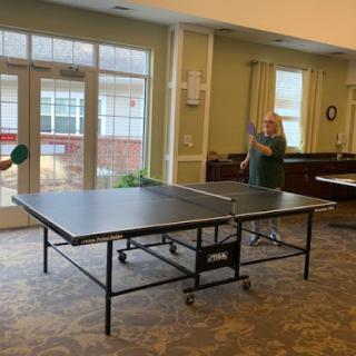 Two players engaged in a spirited game of table tennis indoors.
