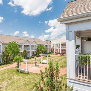A scenic view of a modern apartment complex with well-maintained landscaping under a bright blue sky.
