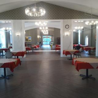 A spacious event venue featuring elegant chandeliers and tables dressed in red, perfect for gatherings.