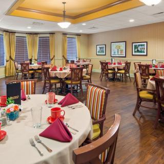 A well-decorated dining room with neatly arranged tables and chairs, featuring elegant table settings.