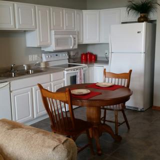 A cozy kitchen with white cabinets and a small wooden dining table set.