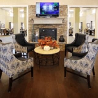 A cozy waiting area with stylish chairs, a fireplace, and a television.
