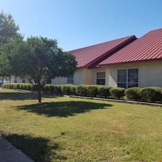 A sunny day at a well-maintained building with a red roof and green surroundings.