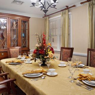 An elegantly set dining room with a flower centerpiece and a chandelier above the table.