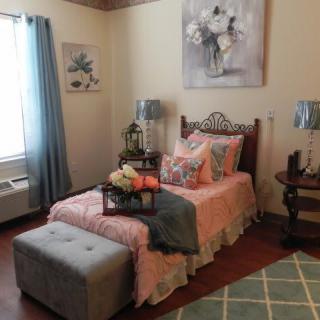 A cozy bedroom with a well-decorated bed, soft lighting, and tasteful artwork.