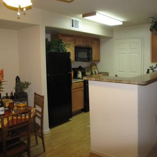 A cozy kitchen with a dining area, featuring wooden cabinets and modern appliances.