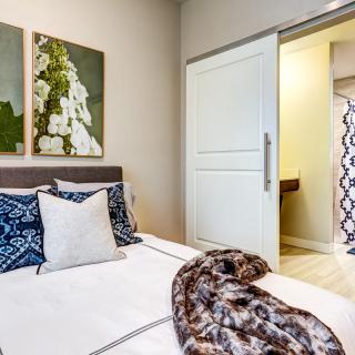 A cozy bedroom with modern decor and artwork above the bed.