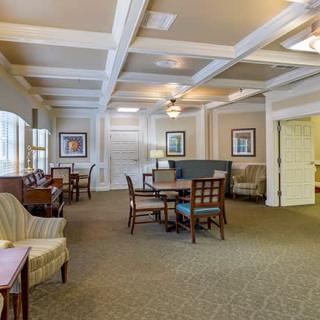 A spacious lounge area with tables, chairs, and decorative paintings.