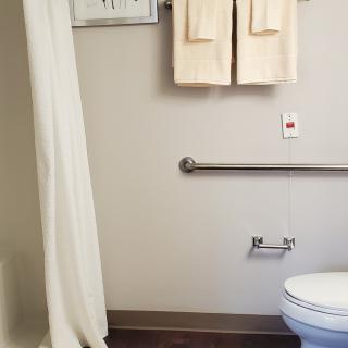 A clean and well-organized bathroom with a shower curtain, towels, and handrail.