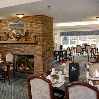 Cozy dining area with a fireplace and elegantly set tables in a restaurant.