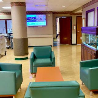 A modern waiting area in a hospital featuring comfortable seating and an aquarium.