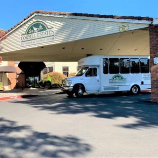 A shuttle bus parked under the awning of a building entrance.